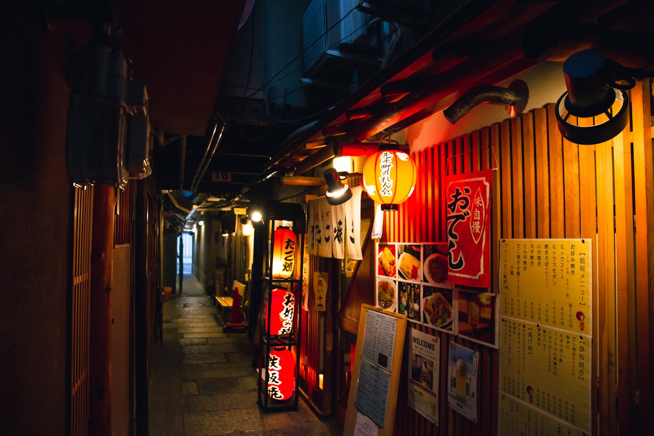 Narrow street with traditional Japanese izakaya bars decorated with hieroglyphs and traditional red lanterns in evening